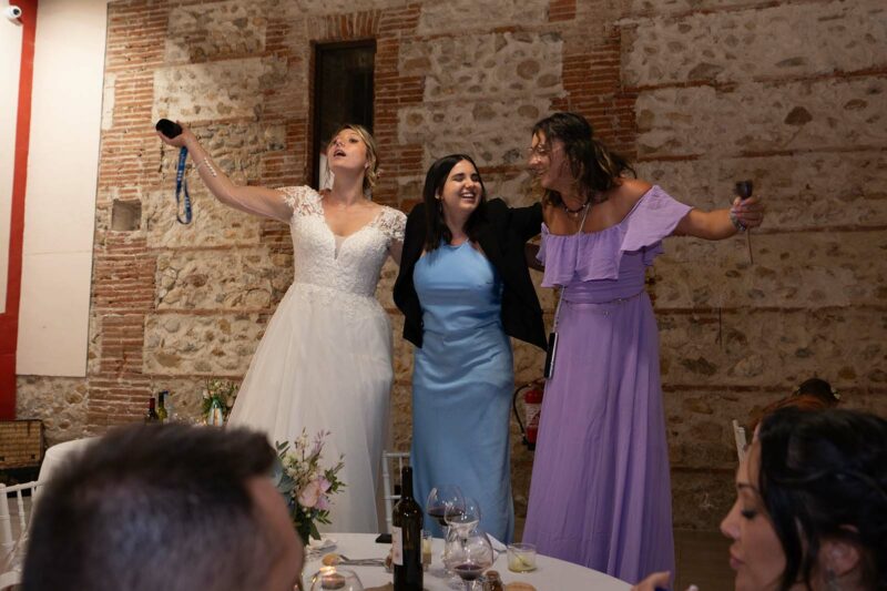 photo d'une soirée de mariage où on voit la mariée accompagnée de deux jeunes femmes debout sur une chaise
