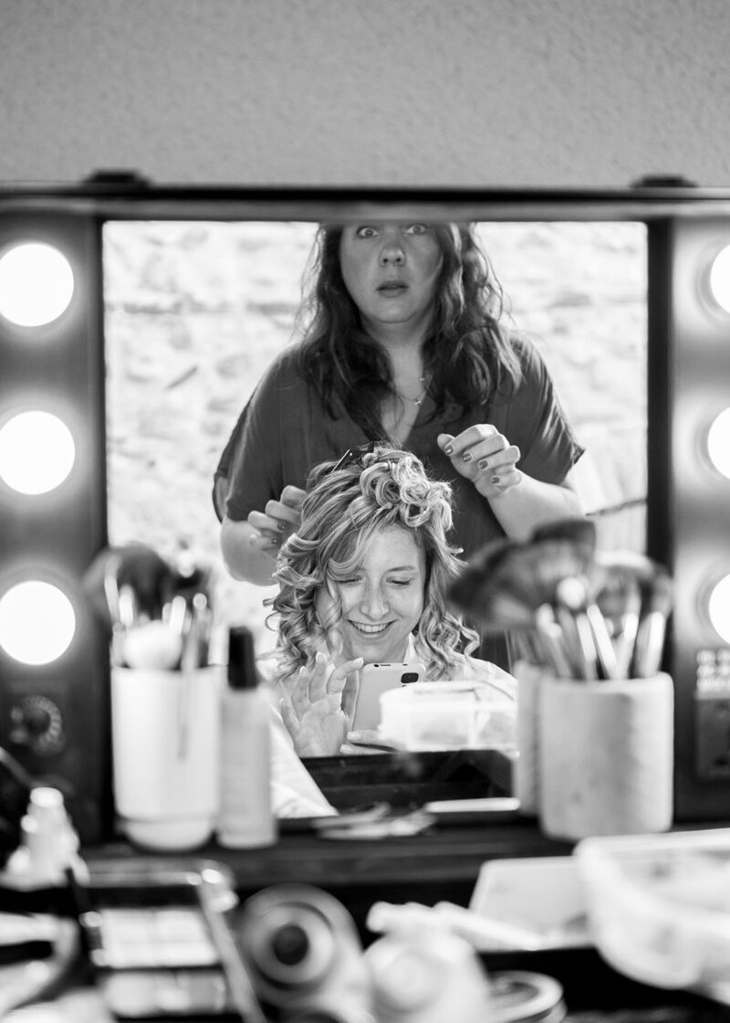 photo noir et blanc d'une femme dans le miroir en train de se faire coiffer