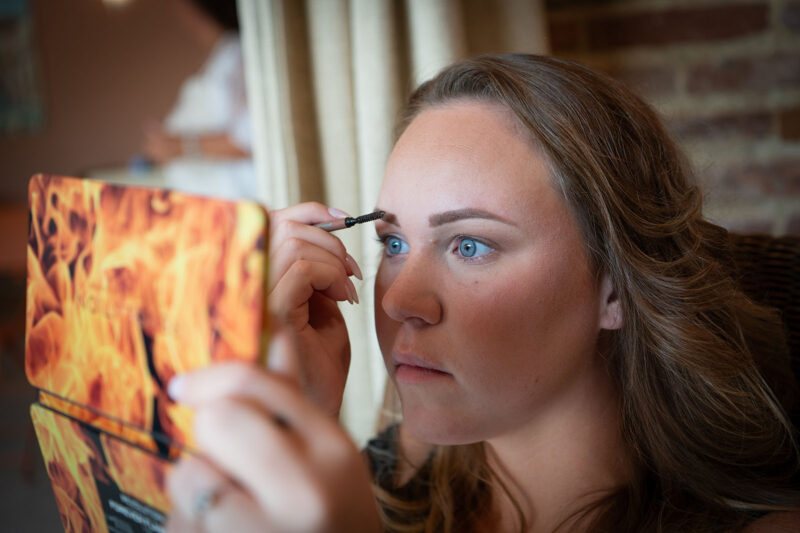 jeune femme en train de se maquiller les sourcils devant un miroir