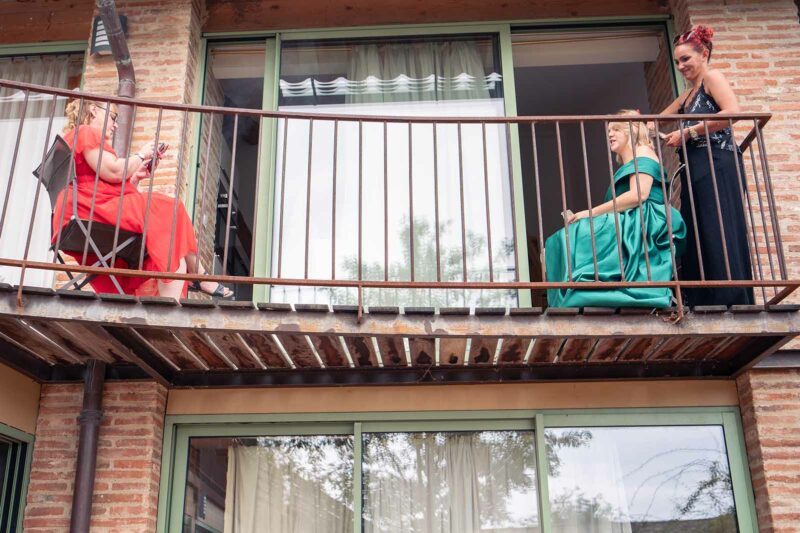 photo prise d'en bas de deux femmes assises l'une en face de l'autre sur un balcon