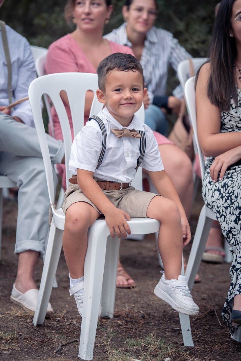 portrait d'un jeune enfant assis sur une chainse habillé avec des bretelles