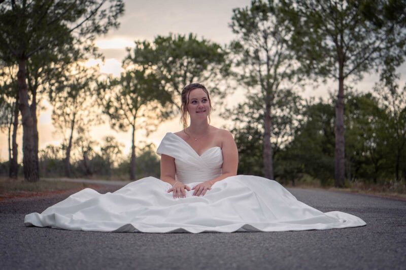 portrait d'une mariée assise dans un chemin au coucher de soleil