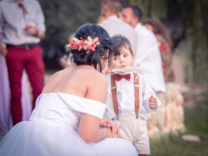 mariée parlant a un jeune enfant portant un fleur de pampa à la bouche