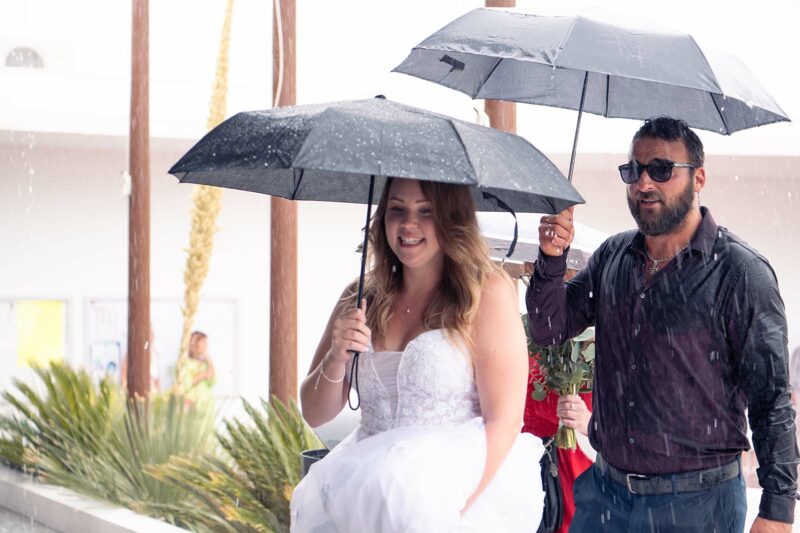 mariée marchant sous la pluie avec un parapluie