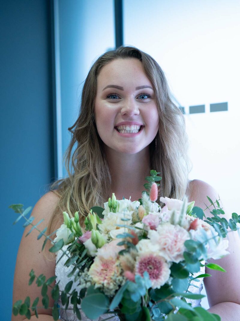 gros plan sur une jeune femme qui sourie et portant un bouquet de fleurs
