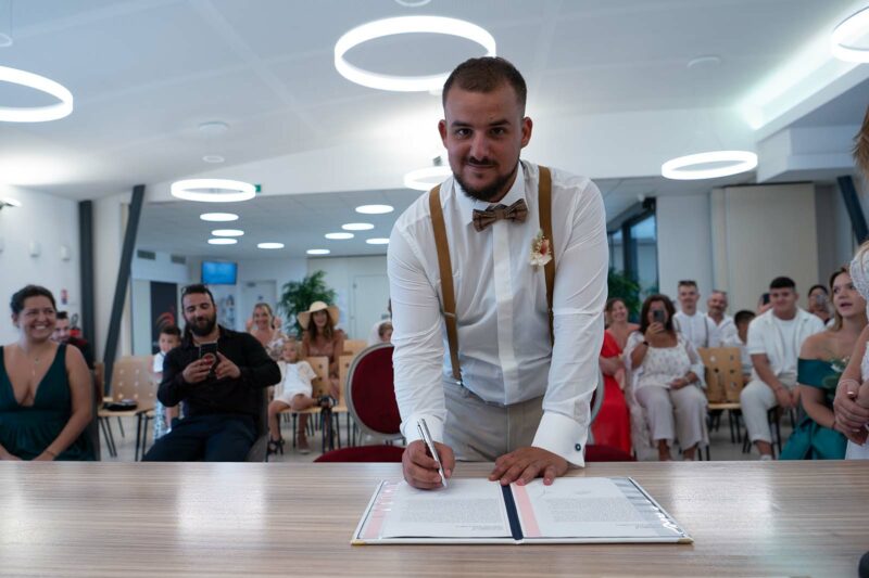 jeune marié signant le registre de mariage durant la cérémonie civile de son mariage