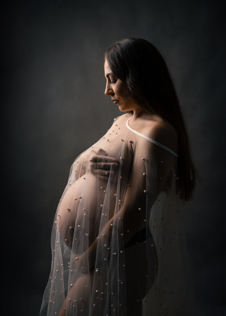 Photo studio d'une femme enceinte portant un voile en tulle perlé