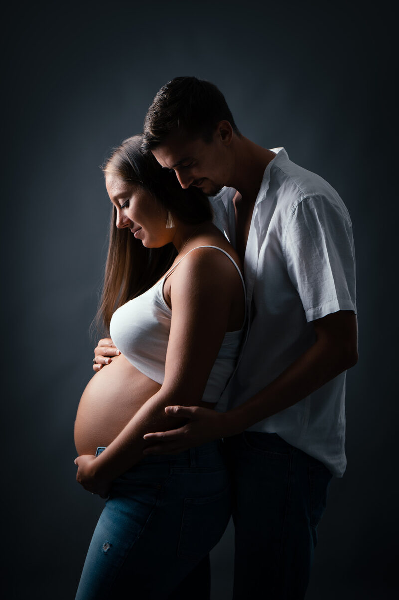 photo studio d'un couple se tenant dans les bras et dont la femme est enceinte