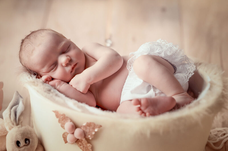 photo studio d'un bébé dans un contenant allongé sur le coté