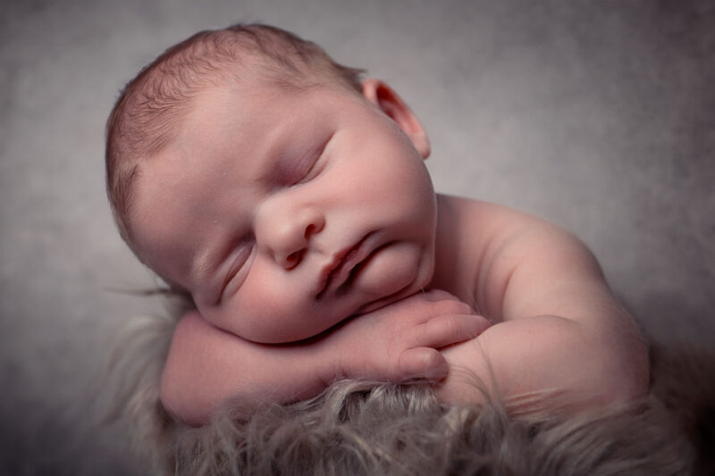 photo studio d'un bébé dormant appuyé sur ses bras