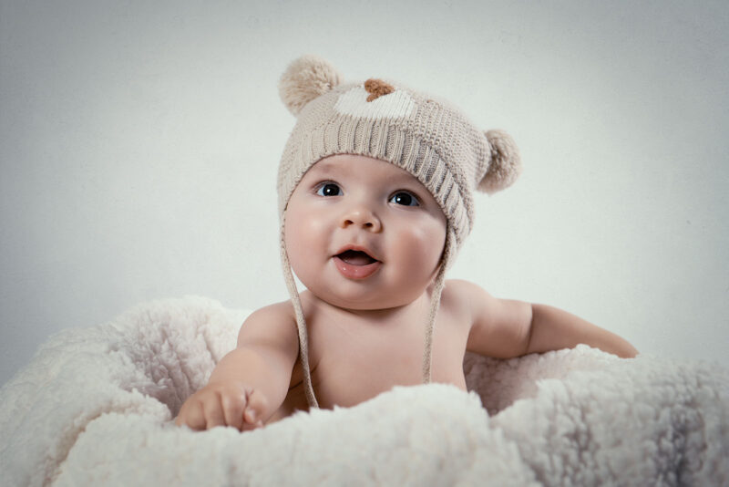 gros plan sur un bébé assis portant un bonnet avec des petites oreilles