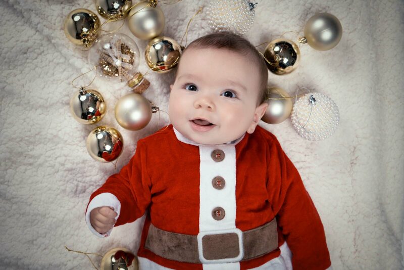 photo prise d'en haut d'un bébé habillé en costume de noël avec des boules de noël posées au sol