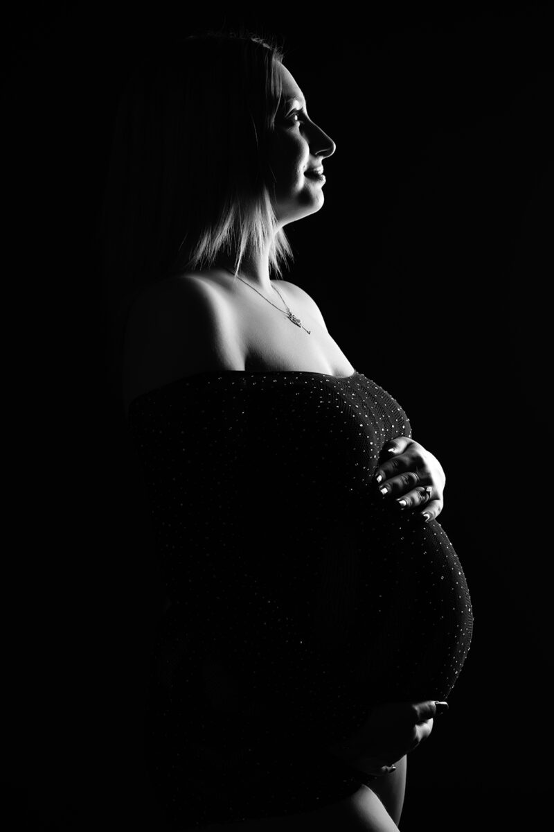 photo noir et blanc d'une femme enceinte prise de profil en clair obscur