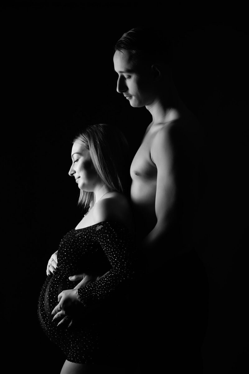 photo noir et blanc d'un clair obscur d'une femme enceinte avec son conjoint prise de profil
