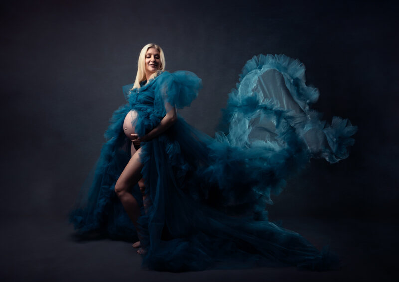 photo studio d'un femme enceinte portant une grosse robe en tulle bleue