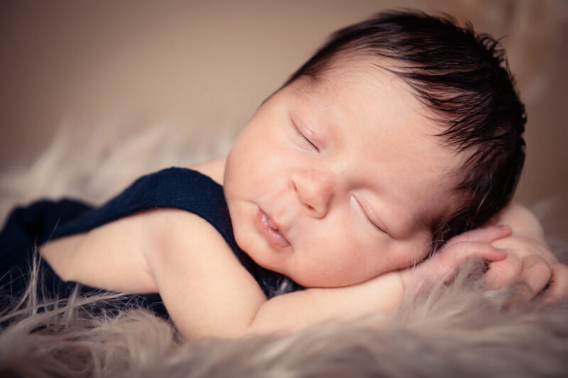 gros plan sur la tête d'un bébé qui dort la tête posée sur ses mains