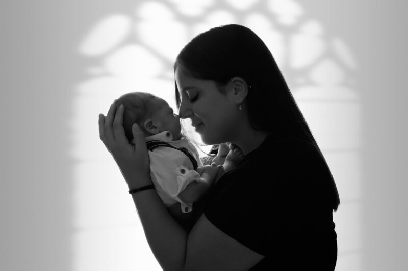 photo noir et blanc d'une maman avec son bébé prise en contre jour