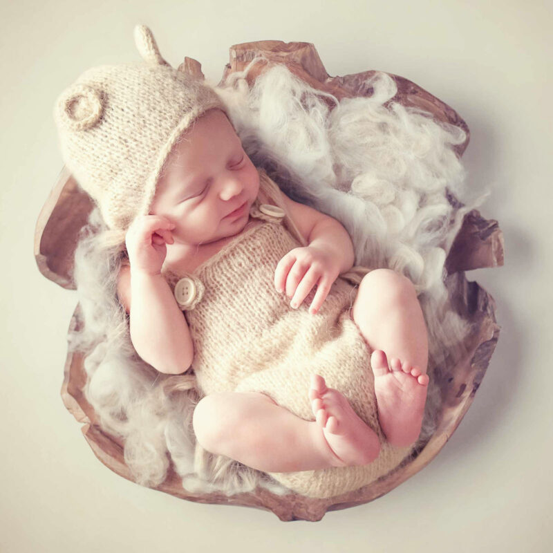 photo d'un bébé prise du dessus dans une espèce de grosse coquille en bois