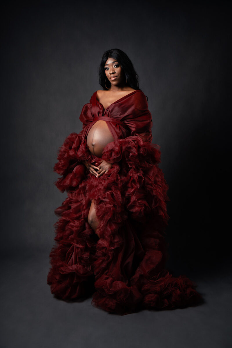 photo studio d'une femme enceinte portant une grosse robe en tulle rouge