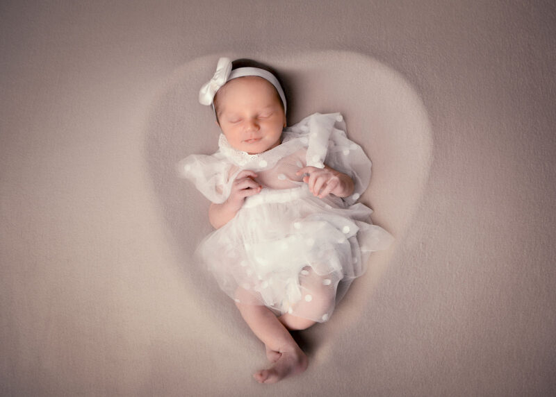 photo studio d'un nouveau-né dans un contenant en forme de cœur