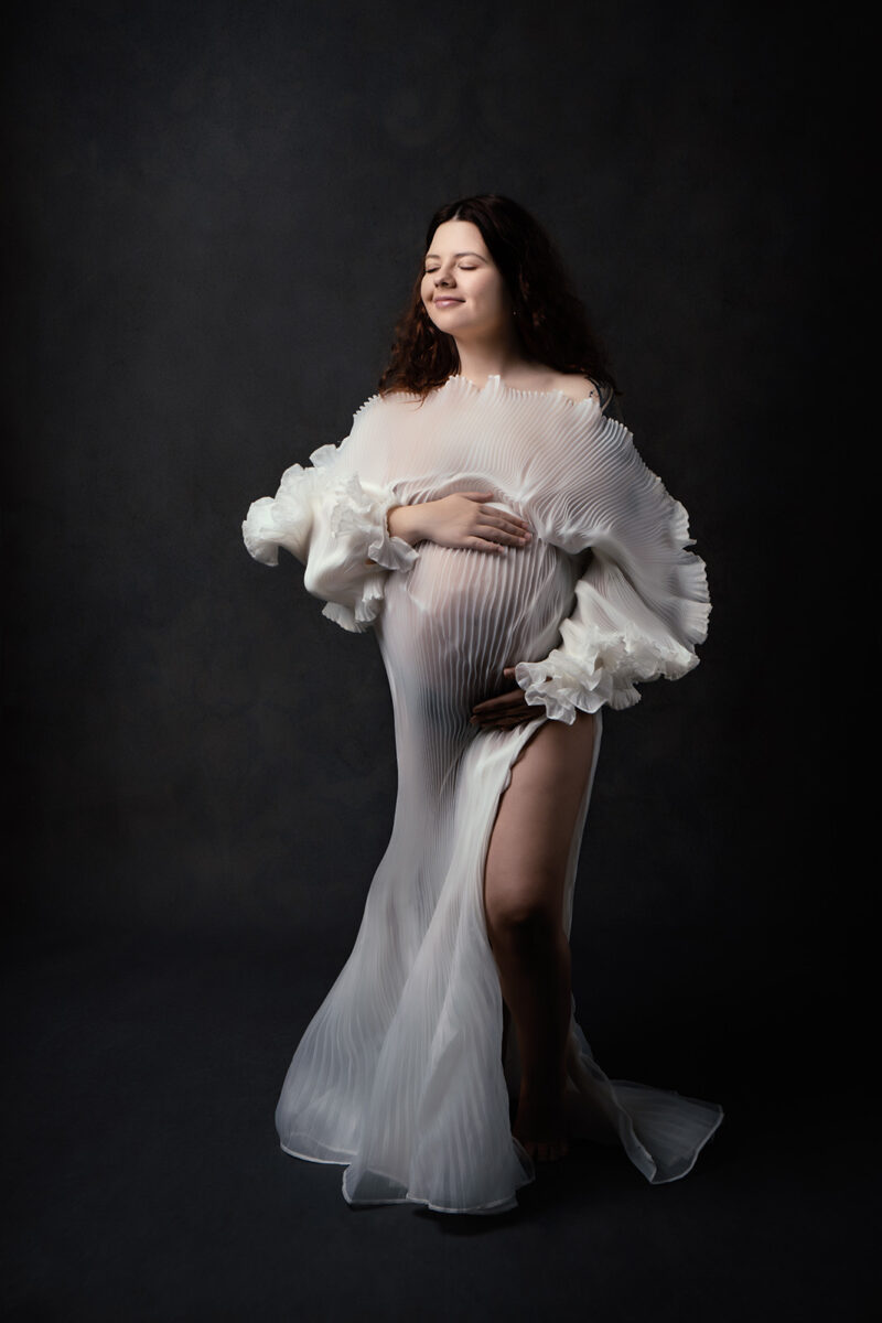 Photo studio d'une femme enceinte habillée d'une robe blanche en tulle