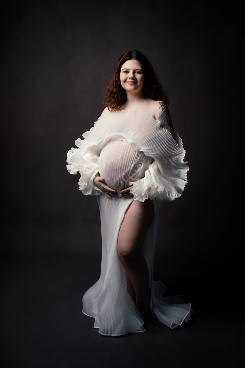 Photo studio d'une femme enceinte habillée d'une robe blanche en tulle