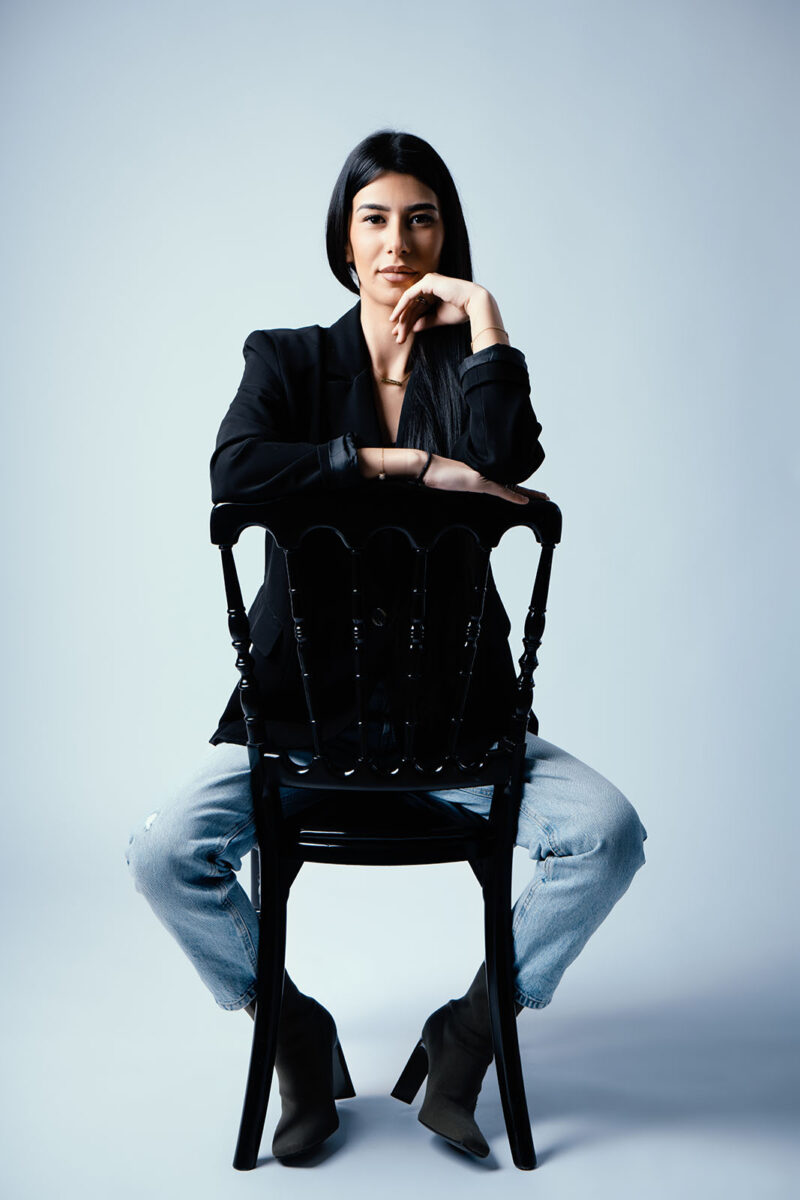 portrait studio d'une femme se tenant assis sur une chaise noire