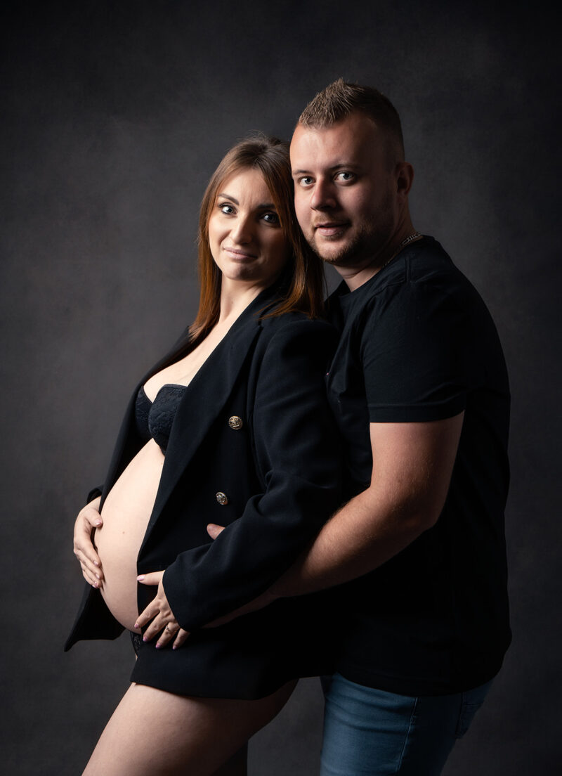photo studio d'une femme enceinte avec son conjoint se tenant derrière elle