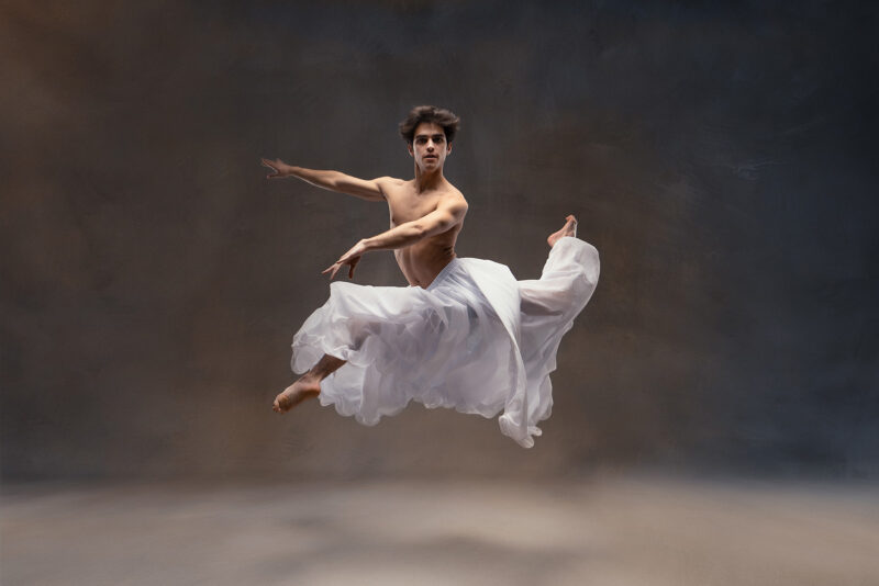 photo studio d'un danseur classique exécutant un saut en jupe blanche