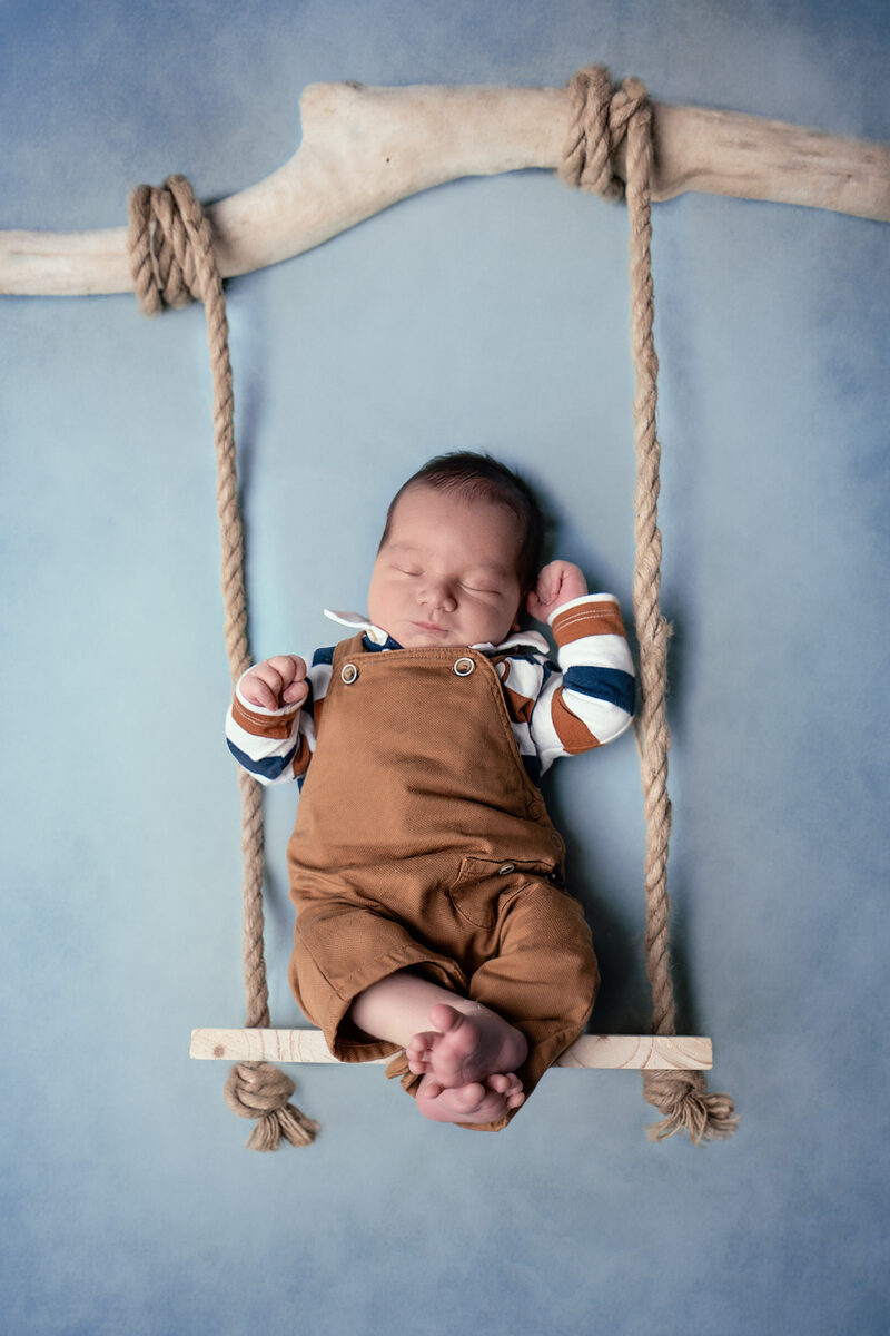 photo studio d'un bébé posé sur une balançoire