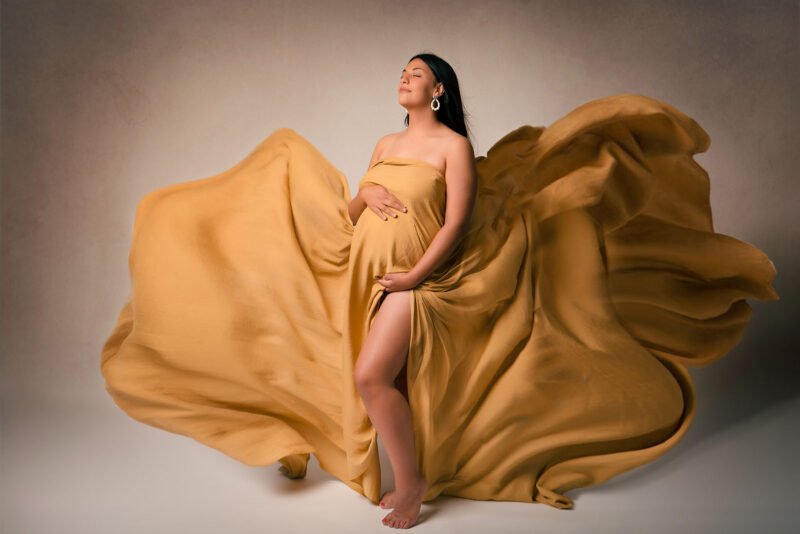 photo studio d'une femme enceinte habillée d'un voile volant de couleur jaune