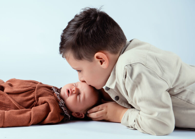 photo d'un petit garçon faisant un bisou sur la tête de sa petite sœur