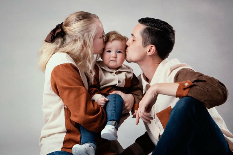 photo studio de deux parents embrassant leur petit enfant