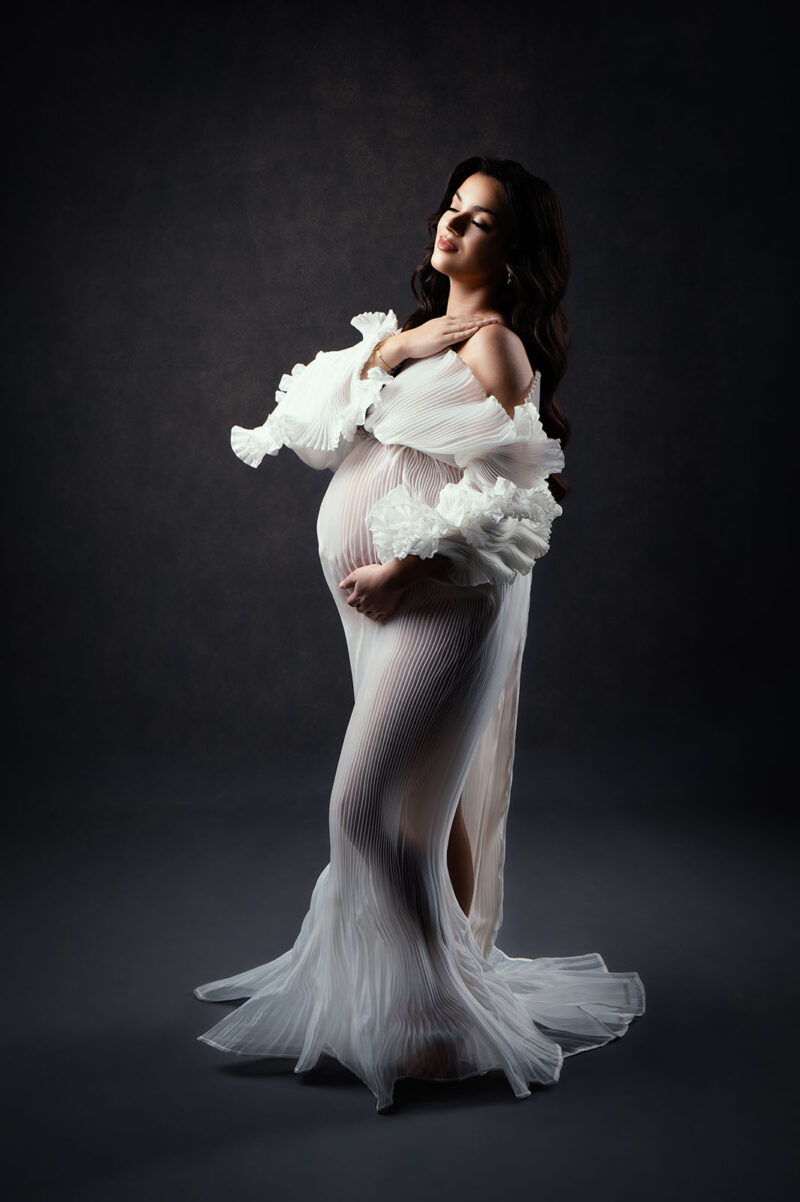 photo studio d'une femme enceinte portant une robe de créatrice blanche