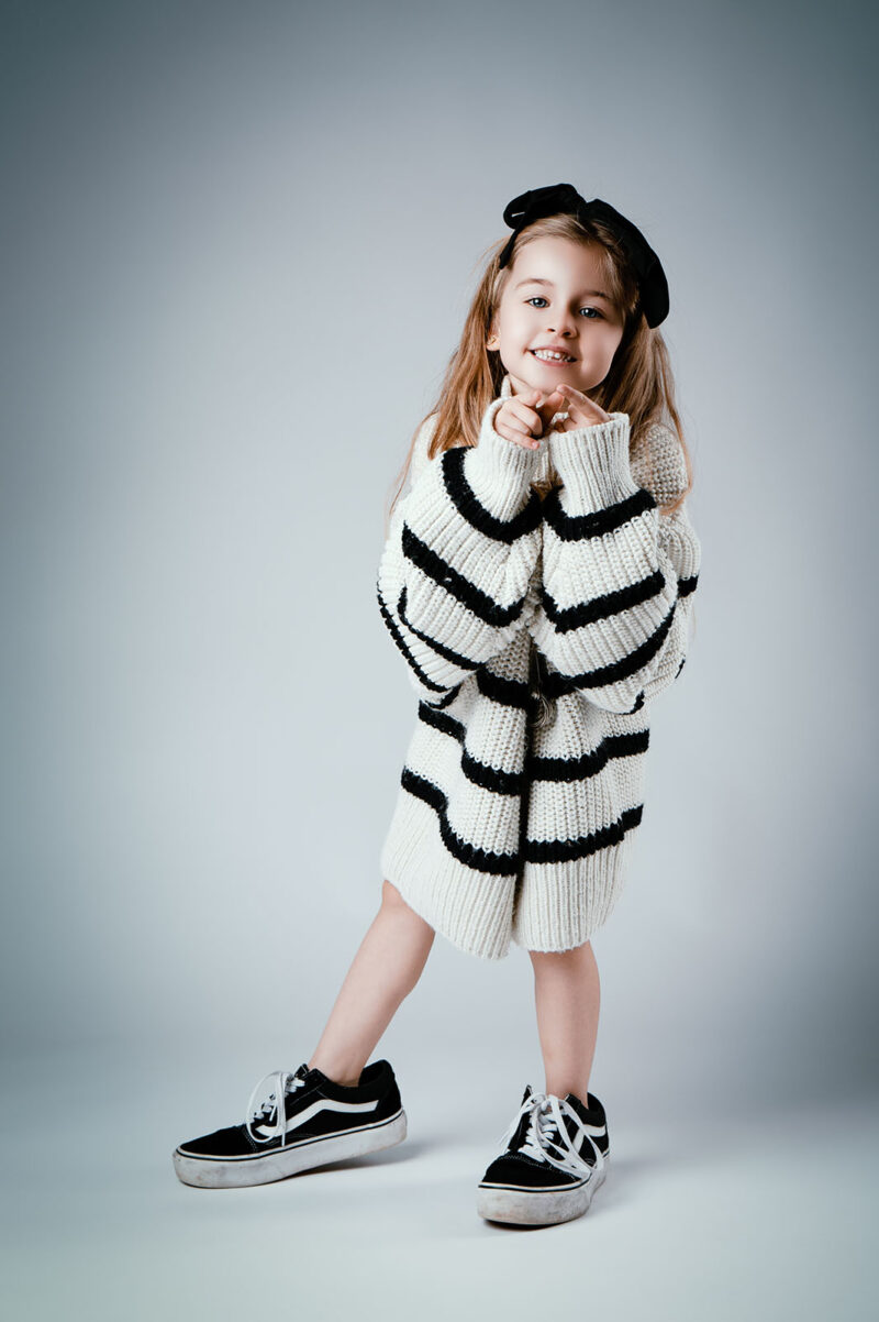 photo studio d'une petite fille sur fond blanc portant les vêtements de sa maman
