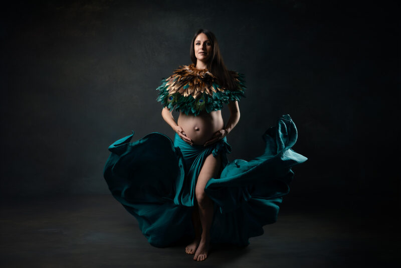 Photo studio d'une femme enceinte portant un col en plume et un voile volant en guise de jupe