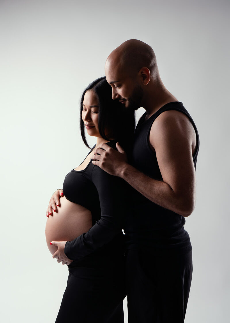 photo studio d'un couple dont la femme est enceinte, tous les deux sont habillés en noir