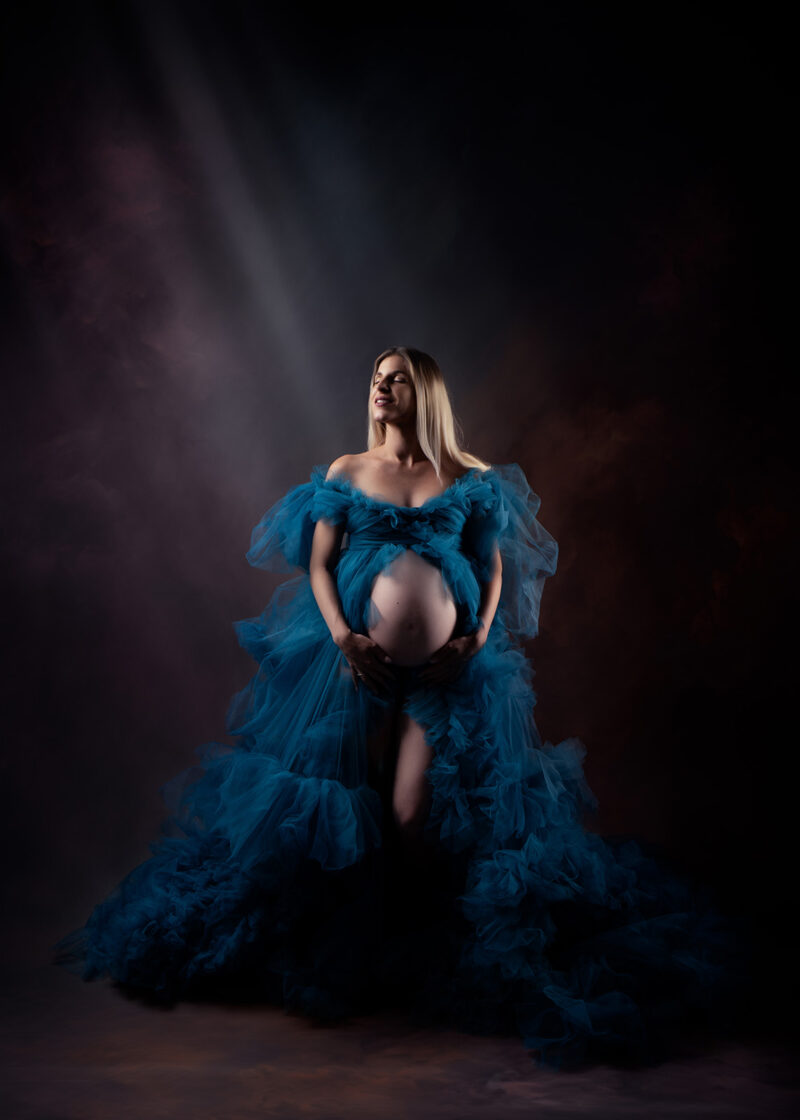 photo studio d'une femme enceinte portant une grosse robe en tulle bleu