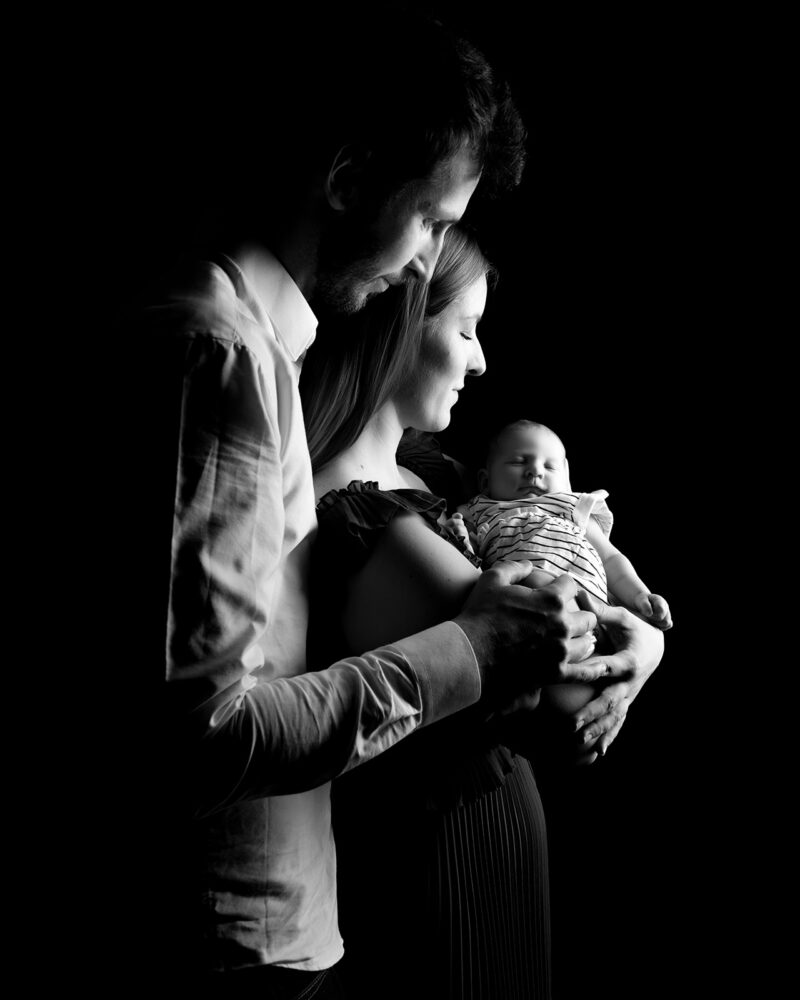 clair obscur où l'on voit deux parents portant un bébé