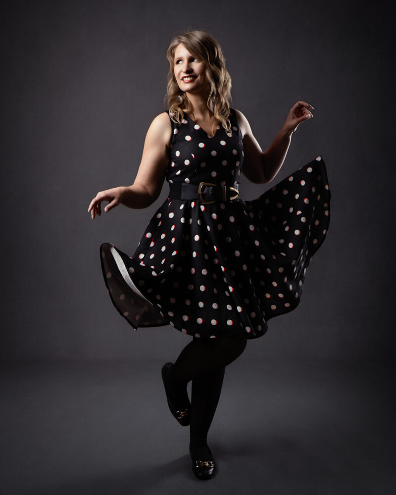 Jeune femme portant une robe de Pin UP qu'elle lève avec ses mains en regardant sur le coté