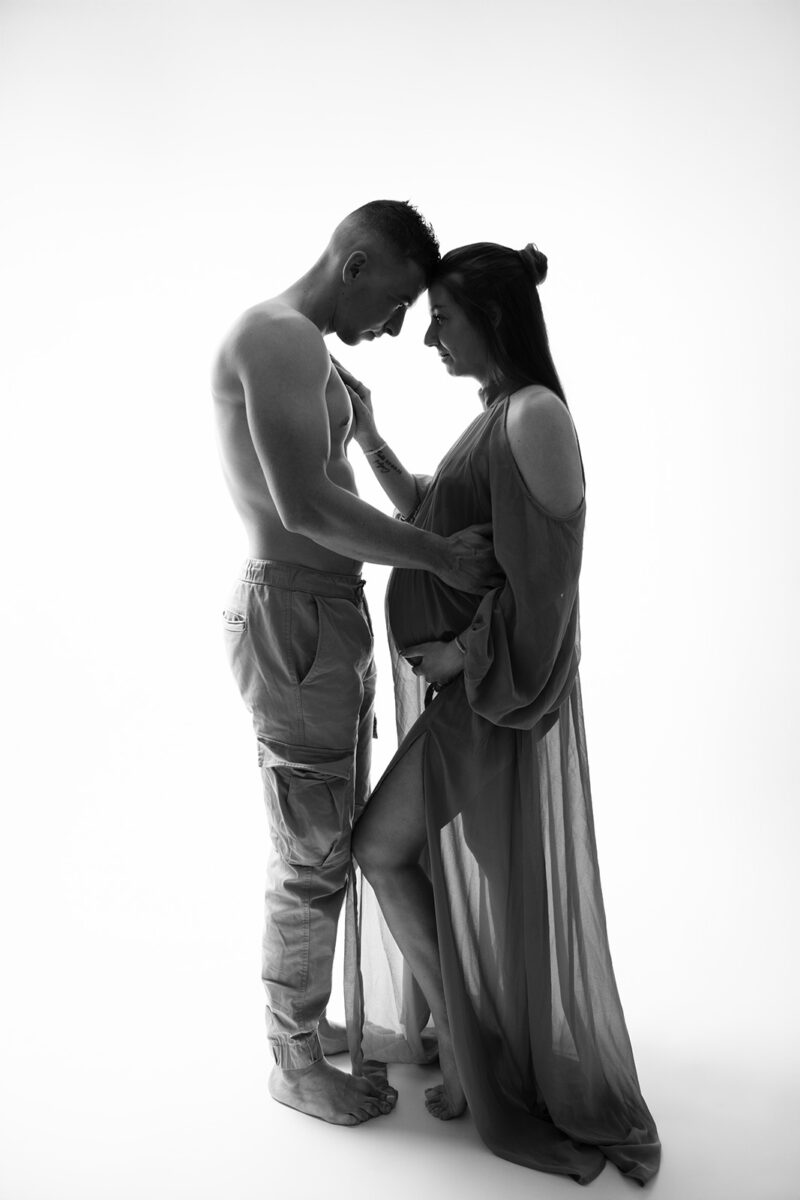 photo studio d'une femme enceinte avec son conjoint prise en contre jour