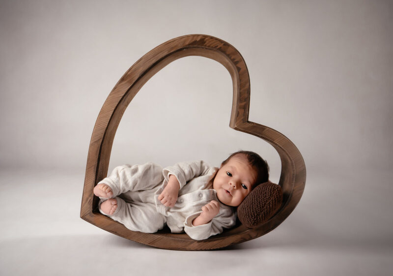 photo studio d'un bébé posé dans un cœur en bois
