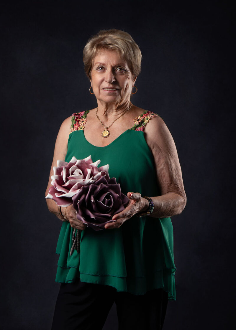 photo studio d'une femme âgée tenant des fausses fleurs dans sa main