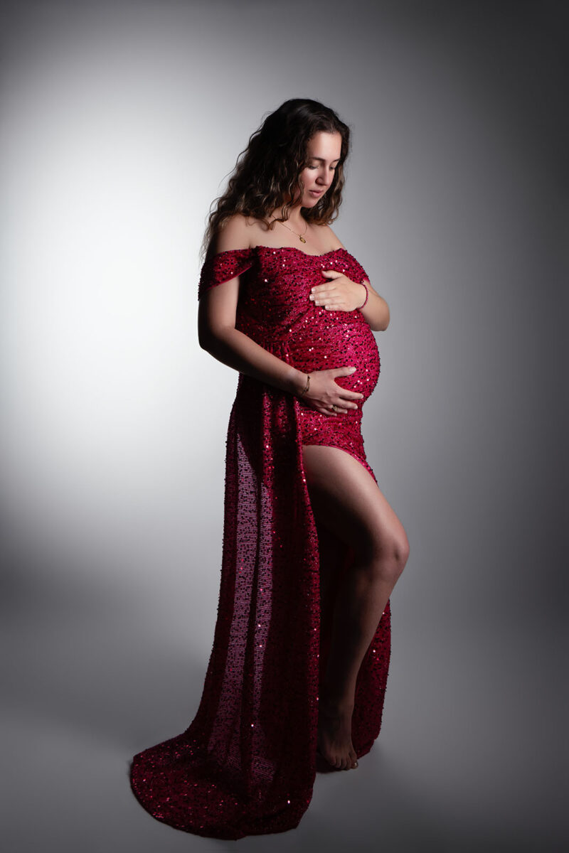 photo studio d'une femme enceinte portant une robe rose pailletée